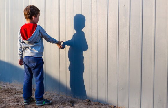 boy and his shadow. Lonely little child playing with his shadow outside. the concept of autism and loneliness. Copy space for your text